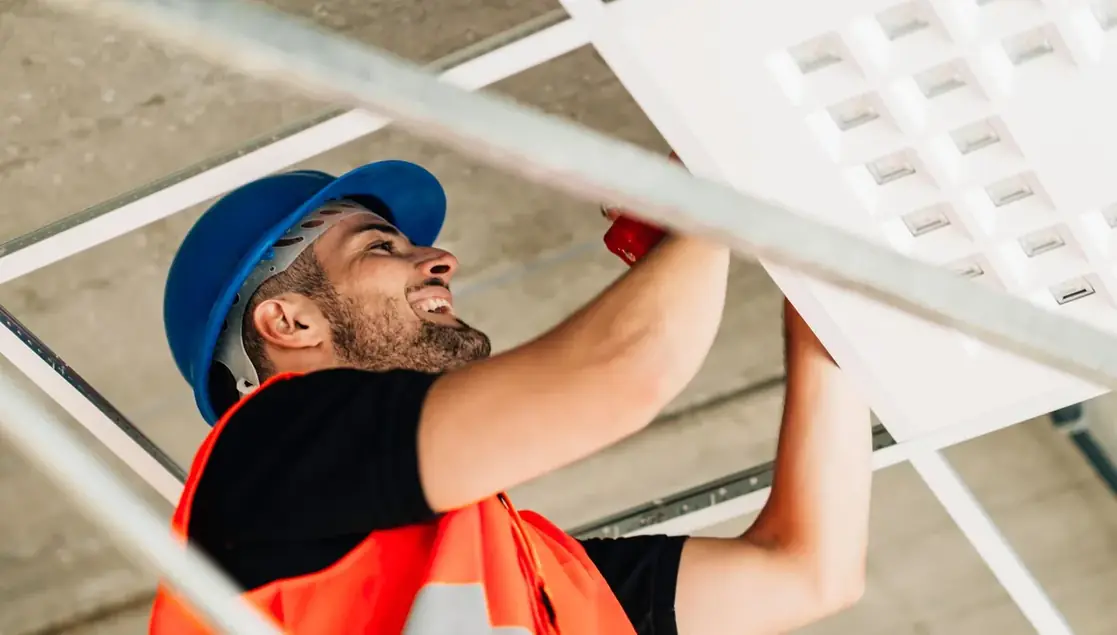 Trabalhador de capacete instalando estrutura de forro em obra